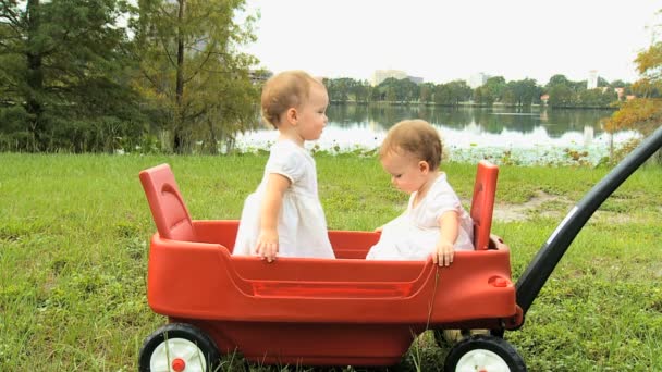 Twin girls standing in plastic cart — Stock Video