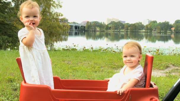 Twin girls standing in plastic cart — Stock Video