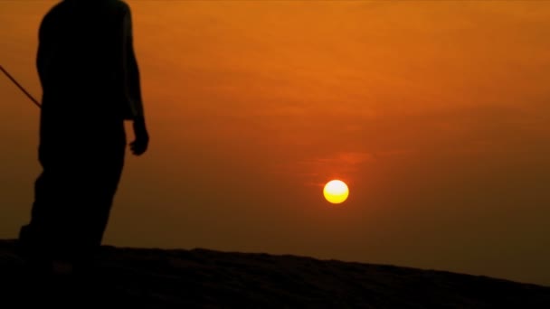 Hombre caminando sus camellos por el desierto — Vídeos de Stock