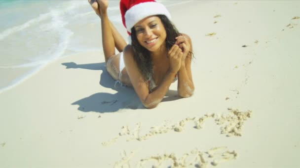 Retrato sonriente chica hispana con sombrero de Navidad en la playa — Vídeo de stock