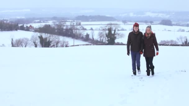 Парень и девушка наслаждаются прогулкой по снегу — стоковое видео