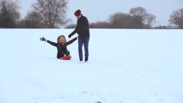 Pareja jugando juguete trineo en invierno — Vídeos de Stock