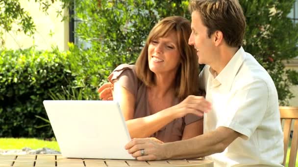 Ζευγάρι στο σπίτι με κήπο με φορητό υπολογιστή — Αρχείο Βίντεο