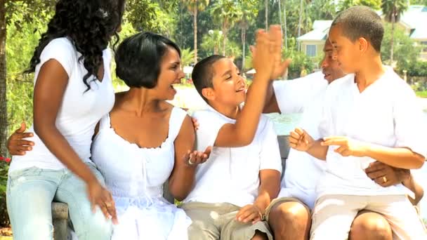 Афроамериканская семья на скамейке в саду — стоковое видео