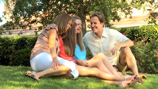 父母与十几岁的女儿坐在草地上 — 图库视频影像