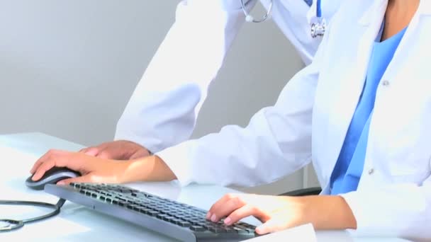 Врачи, использующие компьютер в медицинском кабинете — стоковое видео