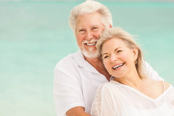 Happy mature male female Caucasian couple living a healthy outdoor leisure lifestyle on a Caribbean beach