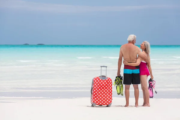 幸せな成熟した白人系アメリカ人の男性のカップルは シュノーケリングやスーツケースと水着で熱帯ビーチで引退を楽しんで — ストック写真