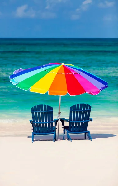 Bahamas Travel vacation beach sun loungers with colorful umbrella on golden sand aquamarine ocean Gulf of Mexico Caribbean Sea USA