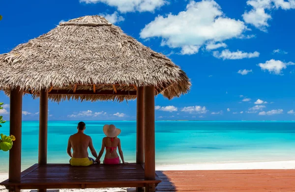 Loving Caucasian male and female couple in tropical hut enjoying vacation and sea view on the beach outdoor Caribbean