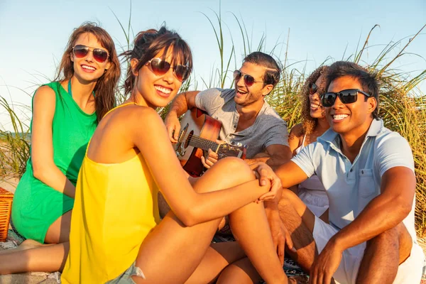 Smiling Young Multi Ethnic Friends Wearing Sunglasses Sitting Beach Sunset — ストック写真