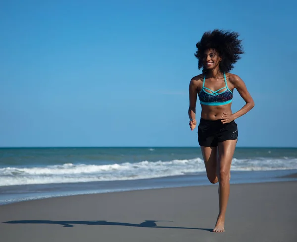 海によってビーチでジョギングスポーツ服の幸せな若いアフリカの女性のための健康的な屋外運動 — ストック写真