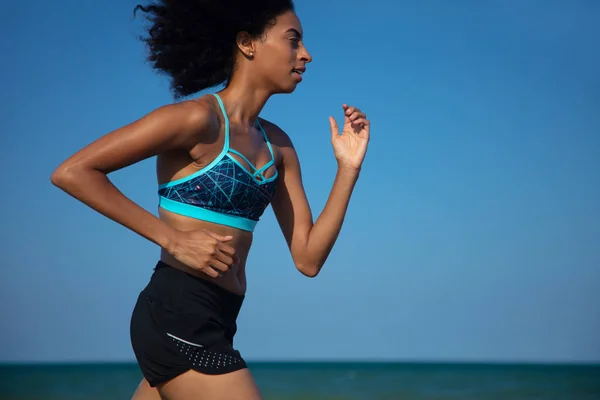 海によって実行されている休暇中に若いアフリカの女性にフィット屋外で運動を楽しんで体重減少と心臓の健康 — ストック写真