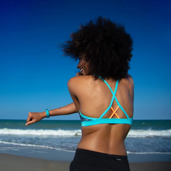 フィット若いですアフリカの女の子でスポーツウェアストレッチで海によって準備楽しいカーディオ運動のためにビーチ — ストック写真