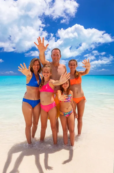 在加勒比海热带海滩上穿着五彩缤纷的泳衣享受闲暇的可爱白人父母和女儿的画像 图库图片