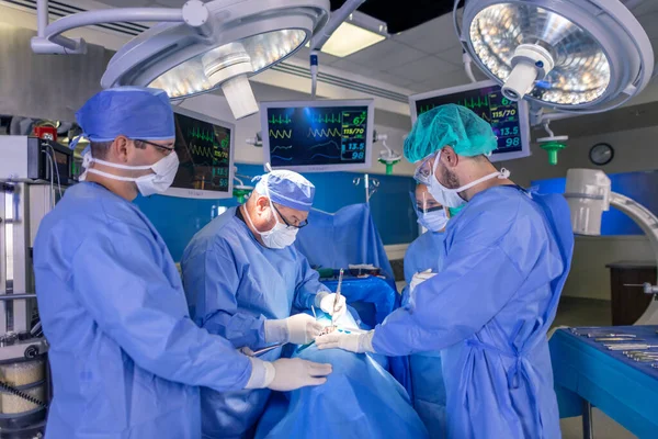 在医院手术室 白种人医疗队穿着个人防护设备 用消毒仪器进行腹腔镜手术 免版税图库照片