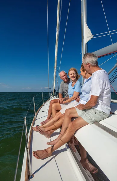 Luxury travel in retirement for senior group of friends sitting together on private yacht sailing the ocean