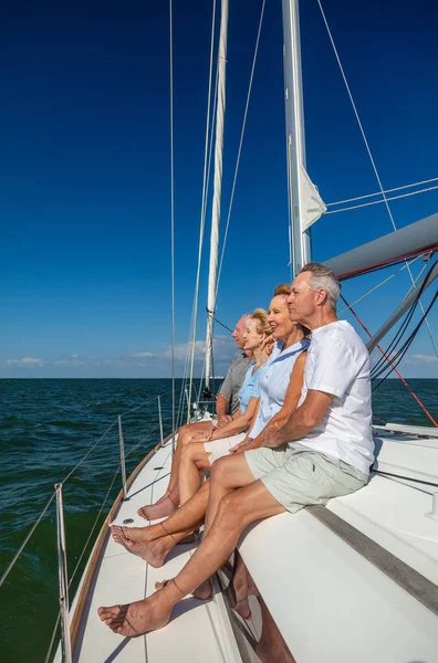 Retired American friends enjoying luxury outdoor lifestyle sitting relaxed on private yacht on fun Summer vacation together