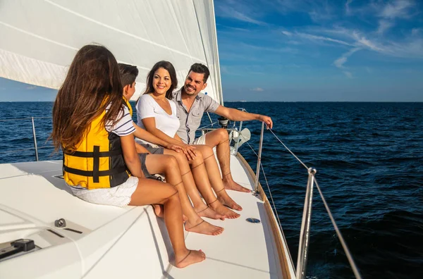 Young Latin American family sitting together on luxury yacht smiling and enjoying freedom outdoors on Summer vacation