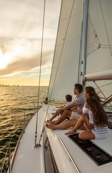 Young Latino family on vacation together sitting on deck of private yacht enjoying carefree sailing adventures at sunset