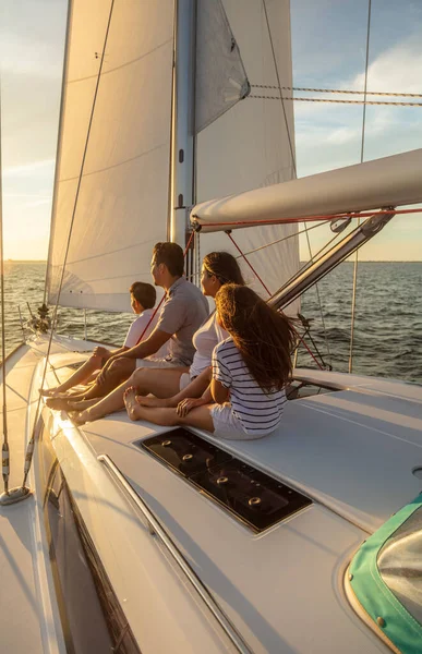 Young Latin American family in casual clothing relaxing on deck of luxury yacht at sunset enjoying outdoor adventures