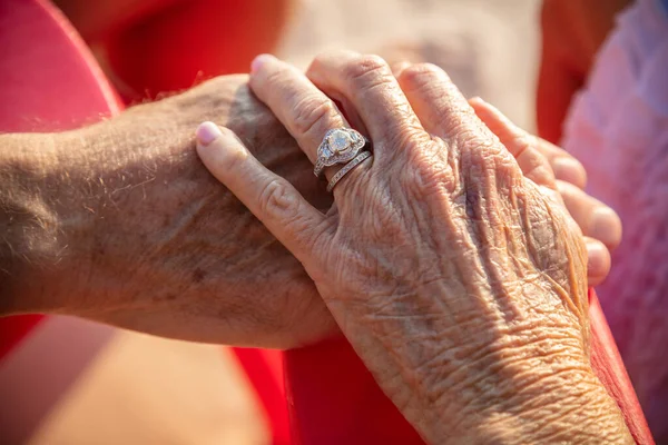 Wedding rings on linked hands of senior Caucasian American couple enjoying retirement together on tropical island beach Bahamas