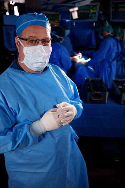 Portrait of Caucasian male medical specialist in hospital operating theatre wearing scrubs with face mask ready to operate