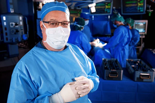 Medical procedure in hospital operating theatre with portrait of male Caucasian doctor beside surgical equipment wearing face mask