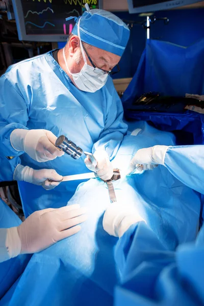 男性白种人医学专家戴着面罩刷子 用无菌手术器械对病人进行手术 — 图库照片