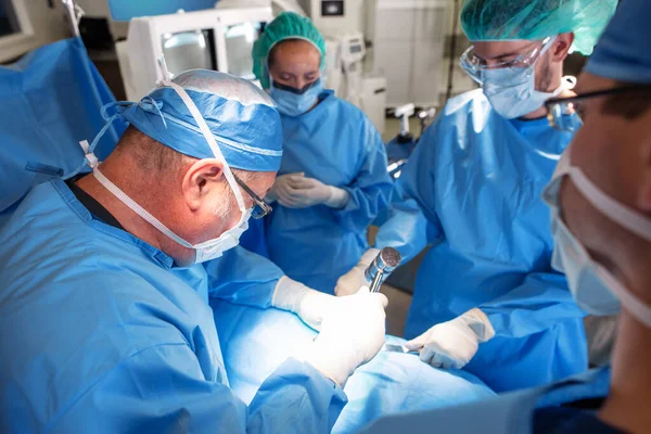 Blanke Mannelijke Chirurg Bijgestaan Door Een Medisch Team Met Gezichtsmaskers Rechtenvrije Stockfoto's