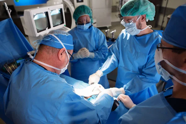 在无菌医院环境下 对麻醉病人实施Ppe手术的白人男性外科医生和专业医疗小组 免版税图库照片