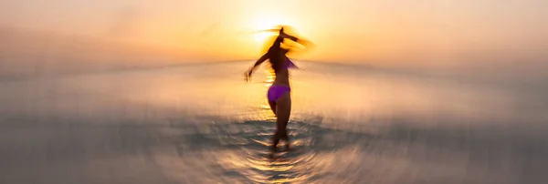 動きぼやけたパノラマの幸せなアジアの女の子で水着で楽しいダンスで熱帯の海で日没バハマ — ストック写真