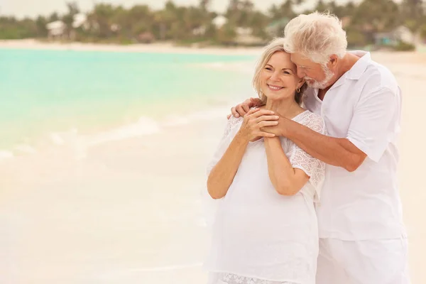 可爱的白种人老年退休夫妇 身穿白色休闲装 一起在豪华的加勒比海度假海滩上散步 图库图片