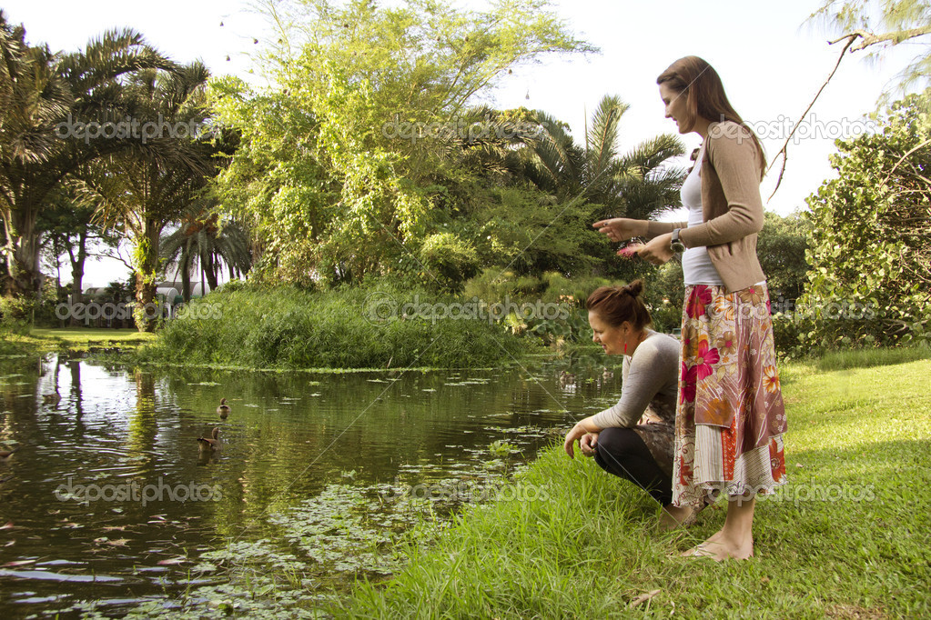 Attractive Sisters feeding ducks at the park