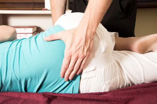 Quiroprático massagem paciente parte inferior das costas, rotação Fotografia De Stock