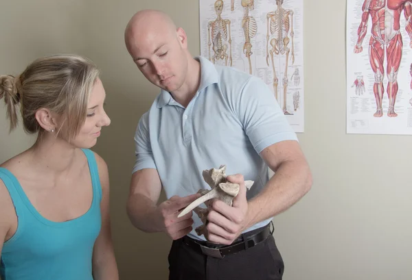 Chiropractor showing female patient sample spine — Stock Photo, Image