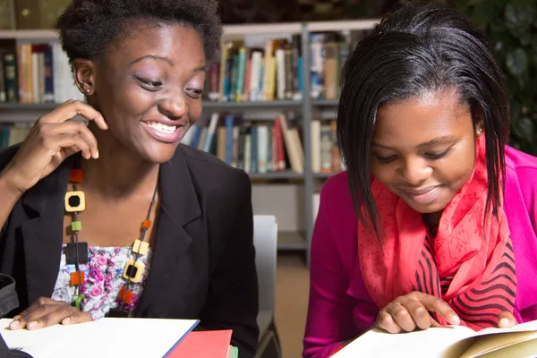 Παιχνιδιάρικο αφρικανικός Αμερικανός σπουδαστές στη βιβλιοθήκη — Φωτογραφία Αρχείου