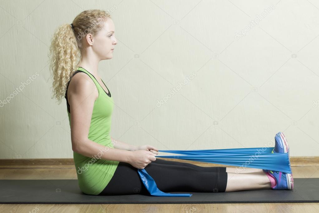Young Female Pilates Instructor using rubber Band