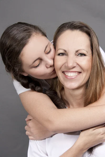 Juguetona hija adolescente besando a mamá en la mejilla — Foto de Stock