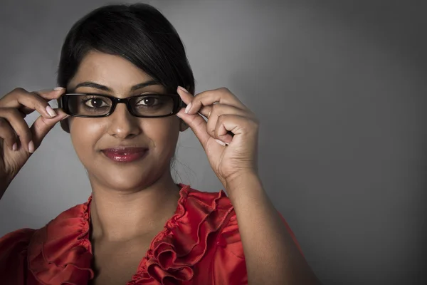 Junge Frau hält ihre gerahmte Brille mit den Fingern — Stockfoto