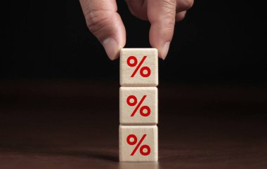 Finans ve İpotek Faiz Oranı Fikir El, yüzdelik sembollerle yukarı doğru yükselen tahta küpleri yerleştirdi. koyu bir arkaplanda.