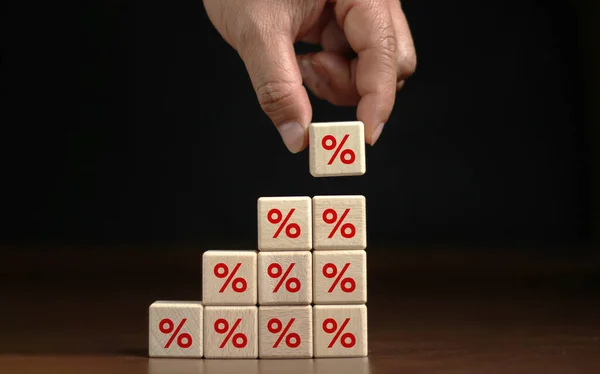 Finance and Mortgage Interest Rate Ideas Hand placed wooden cube blocks rising on top with percentage symbols up direction symbols. on a dark background.