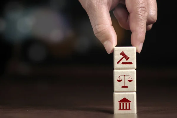 Elle yerleştirilmiş ahşap küp adalet hukuku ve adalet simgesi iş simgesi modern istiflenmiş küp blok tasarımı saray sembolleri, ölçek ve adalet akıllı gri arka planda ve kopyalama alanı.