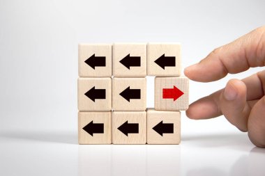 El ele tutuşan ahşap blok ve kırmızı ok ters yöne bakan siyah oklar, Eşsiz, farklı düşün, bireysel ve kalabalığın konseptinden uzak dur. 