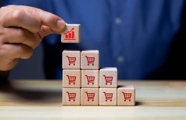 Hand arranging wood block stacking with icon Graph and shopping cart symbol upward direction,