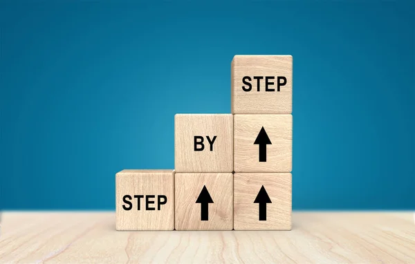 Ahşap bir küp üzerinde adım adım sözler Kariyer başarıları veya gelişmeler ve mavi arka plan