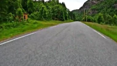 First person view of a nordic two-lane road, forest, mountains