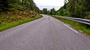 First person view of a nordic two-lane road, forest, mountains