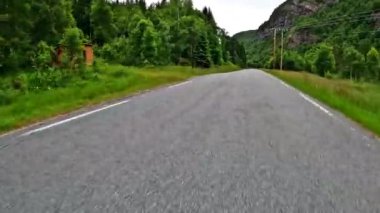 First person view of a nordic two-lane road, forest, mountains