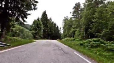First person view of a nordic two-lane road, forest, mountains
